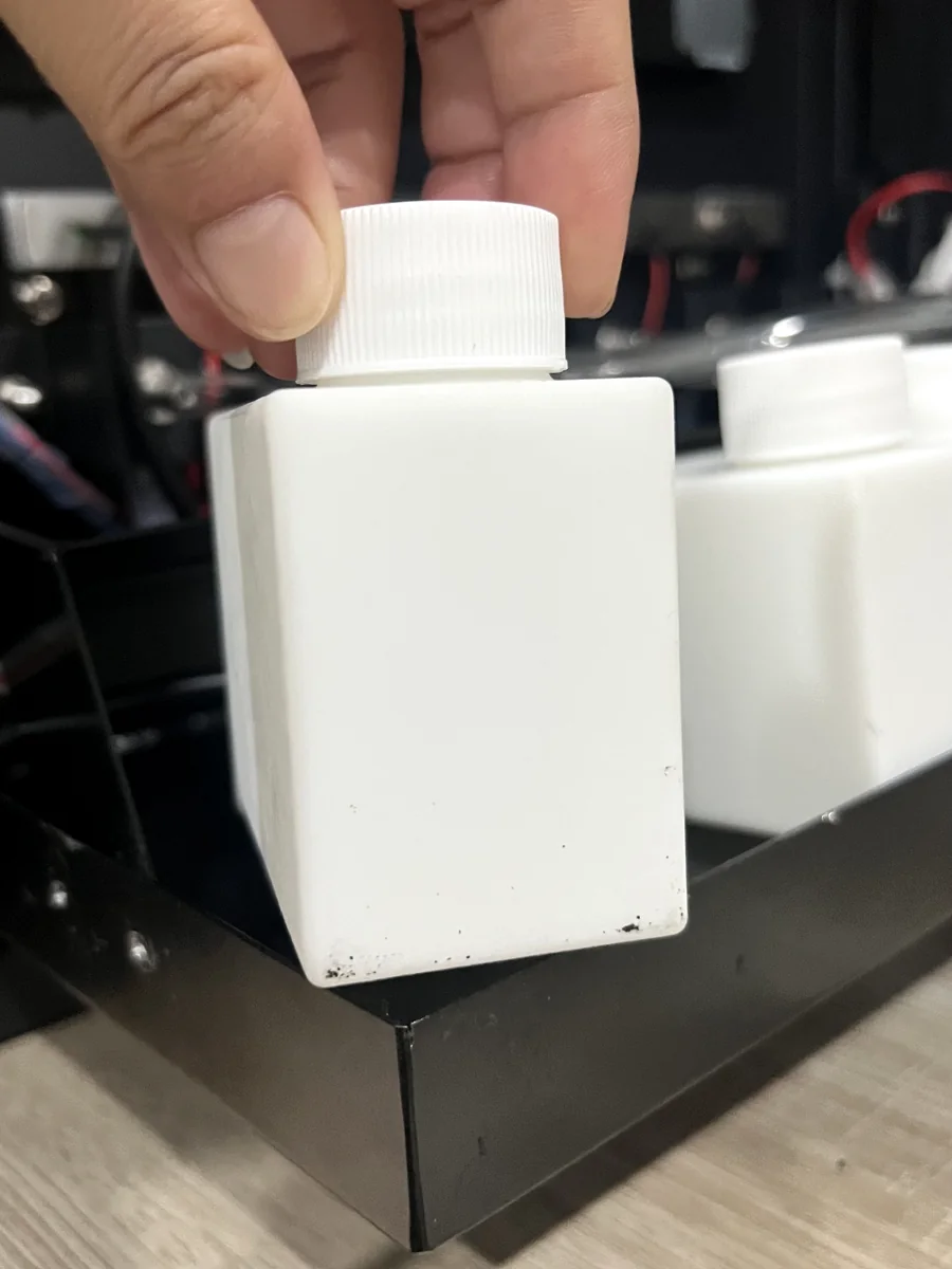 Operator handling a 100 ml fragrance refill bottle inside the machine